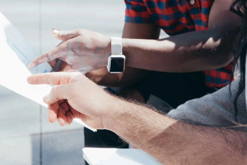 Two people reviewing and discussing documents together outside